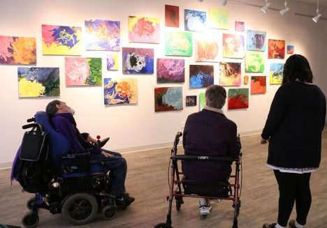 Individuals from MSS in front of a wall of paintings at The Show Gallery