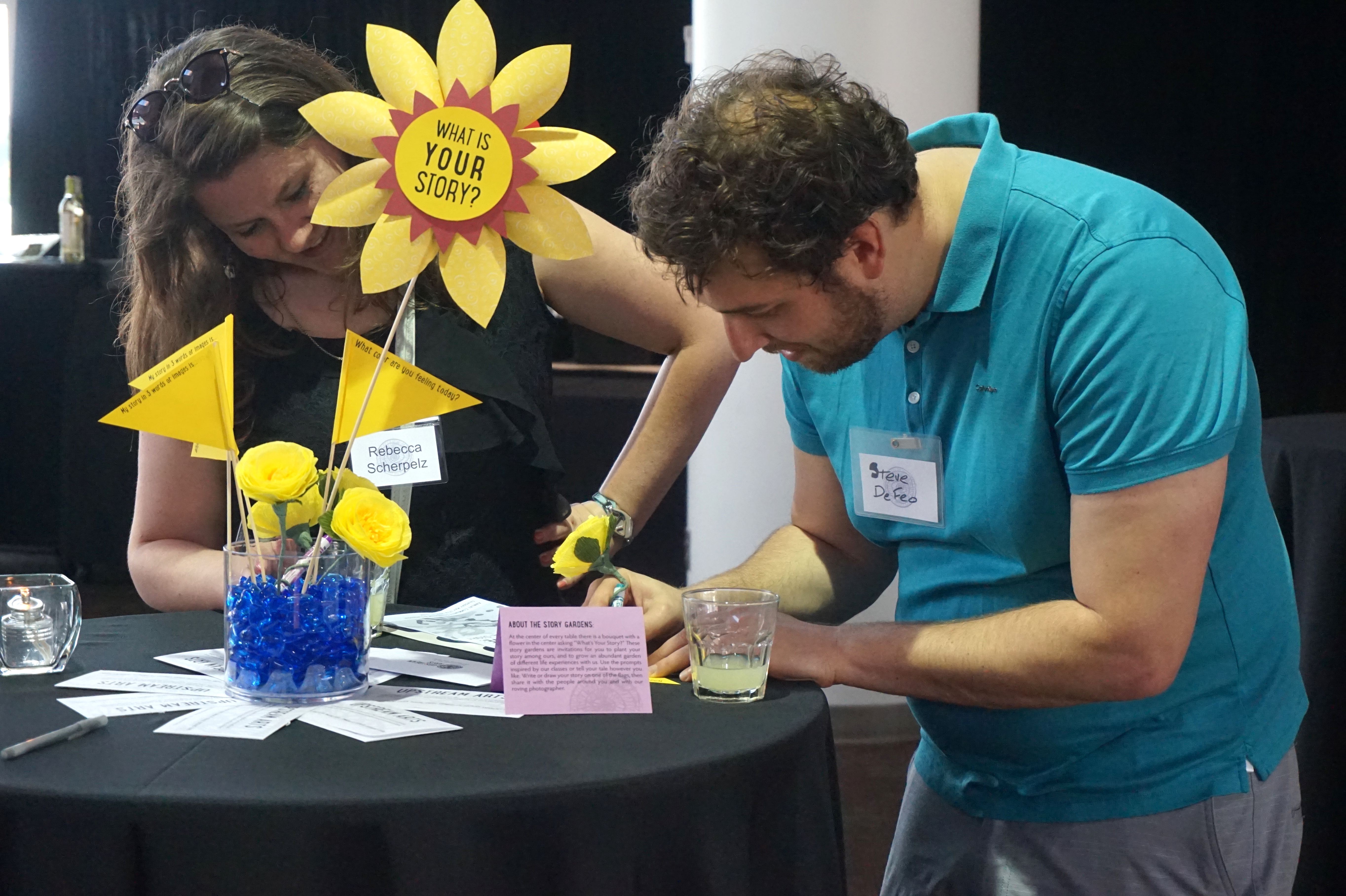 Guests at The Art of We writing answers to the prompts on the Story Garden flowers