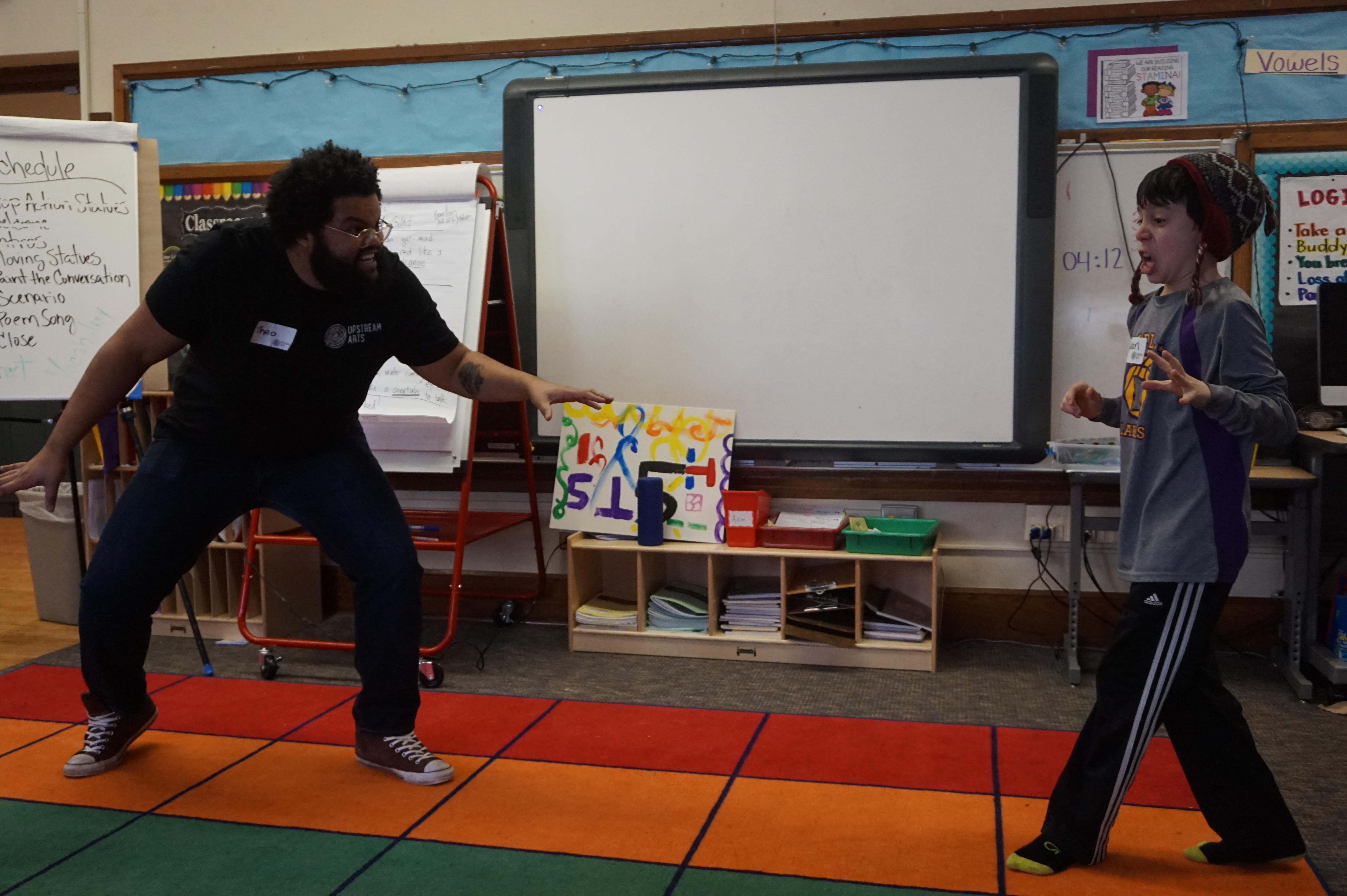 A crouching teaching artist facing a student in an acting scene